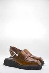 Zueco tipo mocasín color marrón con textura croco y tira regulable al talón.