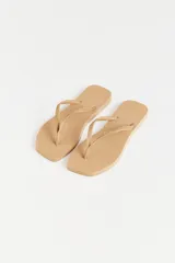 Ojotas color beige con base texturizada y tiras con diseño trenzado y logo de la marca.