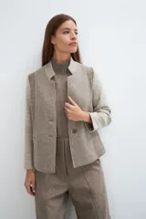 Chaqueta corta color marrón con cuello solapa y diseño con patchwork de telas. Manga larga con detalle de coderas aplicadas. Cierre frontal mediante botones y bolsillos ojal. Con forro.