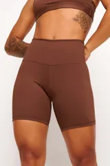 Biker deportiva color marrón de tiro alto, confeccionada en tejido de poliamida y elastano con protección UV y detalles reflectivos.
