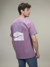 Remera de algodón color azul marino con un estampado gráfico abstracto en la espalda que incluye un círculo azul y formas onduladas en tonos de azul y gris. En la parte superior de la espalda lleva texto impreso.