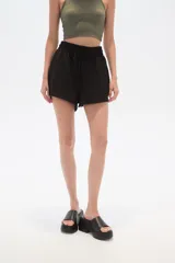 Short negro con textura arrugada, cintura elástica con cordón ajustable y corte holgado.