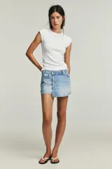 Falda pantalón corta de denim celeste, de tiro alto con cinco bolsillos y cierre frontal cruzado con botones metálicos.