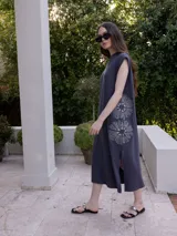 Vestido largo gris con bordado floral blanco en el lateral, de corte recto y sin mangas, con aberturas laterales en el ruedo.