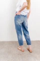 Jean azul de tiro medio y calce relaxed, con roturas amplias y desflecadas.