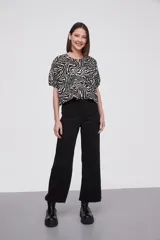 Blusa con estampado animal print en blanco y negro, de mangas cortas abullonadas y cuello redondo.