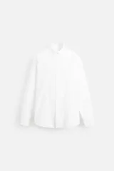Camisa blanca de algodón, corte relaxed fit, cuello abotonado, manga larga con puños abotonados y cierre frontal con botones.