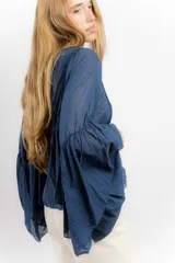 Camisa azul de algodón con cuello alto y mangas largas acampanadas con detalles de puntilla.