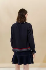 Saco tejido azul marino con cuello redondo, cierre frontal con botones y detalle de volados en cuello y puños.