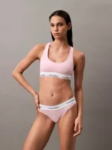 Conjunto Calvin Klein color rosa pálido, compuesto por un corpiño deportivo sin relleno y una tanga, ambos con banda elástica blanca con el logo de la marca.