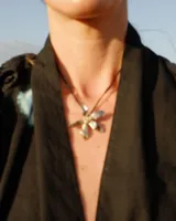 Collar artesanal con dije de flor plateada, realizado con hilo de seda natural teñido a mano.