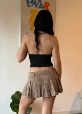 Minifalda marrón a cuadros con pliegues, combinada con un top blanco ajustado.