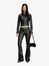 Chaqueta corta estilo biker para mujer, confeccionada en cuero sintético negro con detalles desgastados en las costuras. Presenta cuello mao con cierre a presión, cierre frontal con cremallera, bolsillos delanteros con cremallera y mangas largas.