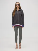 Sweater tejido de algodón color rosa claro, con cuello polo con cierre de cremallera metálica y mangas largas con puños a rayas de colores.