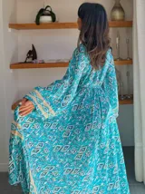 Kimono largo de seda con estampado floral en tonos verde, marrón y beige. Tiene mangas amplias y corte cruzado con lazo ajustable en la cintura.