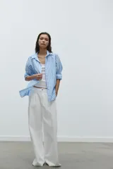 Camisa celeste y blanca a rayas verticales, de popelina, con cuello solapa, escote en pico y mangas largas.