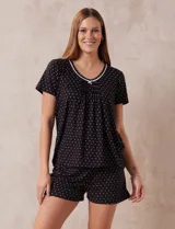 Conjunto de pijama de short y remera en tejido soft estampado a lunares blancos sobre fondo negro, marca René Rofé. Remera de escote redondo con aplique de puntilla y detalle plisado. Short con cintura elastizada.