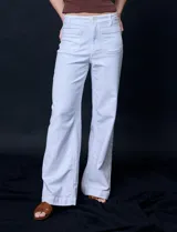 Pantalón de jean blanco de pierna ancha, tiro alto, pretina con pasadores, botón y cierre. Delantera y trasera con bolsillos.