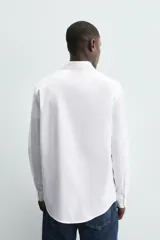 Camisa celeste de corte regular, con cuello italiano, mangas largas con puños abotonados y cierre frontal con botones.