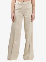 Pantalón palazzo color beige con rayas verticales plateadas y aplicaciones de pedrería. Tiene trabillas, cierre de botón, bolsillos laterales y solapas en la espalda.