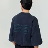 Camiseta negra de algodón con cuello redondo y estampado frontal con el logo de la marca "Fear of God Essentials" en color verde azulado.