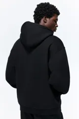 Campera con capucha H&M de felpa negra con interior cepillado suave. Tiene cierre frontal, bolsillos delanteros, puños y bajo en punto acanalado. Corte holgado.