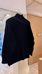 Sweater negro tejido de punto con media polera y trama lineal con textura y relieve.