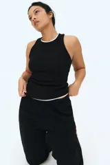 Musculosa negra de punto de algodón acanalado, corte entallado, cuello redondo y ribete fino en escote y sisas.