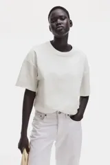 Remera blanca de corte cuadrado, con cuello redondo y mangas cortas.