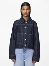 Chaqueta de denim azul oscuro con cuello camisero, cierre frontal con botones en forma de corazón, bolsillos delanteros y costuras en contraste color ocre.