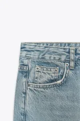 Pantalón de jean celeste de corte recto y tiro medio, con cinco bolsillos y cierre frontal con cremallera y botón metálico.