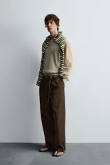 Pantalón relaxed fit color marrón confeccionado en tejido de algodón con estructura twill. Cintura con pliegues frontales, bolsillos laterales en cadera y detalle de bolsillos traseros de doble vivo con botón. Cierre frontal con cremallera y botón.