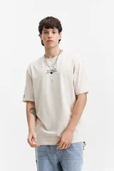 Remera de manga corta color crudo, corte oversize, con estampa en la espalda que incluye flores rojas, texto con el nombre de la marca y la frase 'The Art Society'.