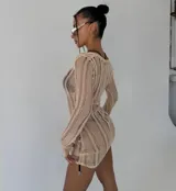 Vestido corto de punto calado color negro, con cuello redondo y mangas largas. Presenta un diseño semi-transparente de silueta ajustada.