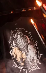 Remera negra de manga corta con cuello redondo y corte oversize. Estampado en el frente con diseño inspirado en la carta del tarot El Carro, con un guerrero en un carro tirado por dos panteras.