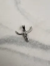 Dije plateado con forma de cráneo de toro con orificio en la frente.