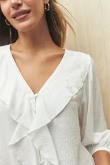 Blusa negra con mangas 3/4 y escote en V con volados.