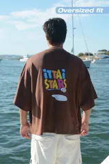 Camiseta celeste de manga corta con cuello redondo y estampado frontal de tres recipientes con cereales. En la parte trasera tiene un estampado grande con el texto "iUTTAi STARS" y un plato con cereales.