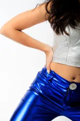 Pantalón largo de cuero sintético verde metalizado, de corte acampanado con aberturas laterales con botones a presión.