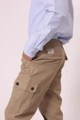 Pantalón cargo color beige con bolsillos laterales con solapa y cierre de botón a presión.