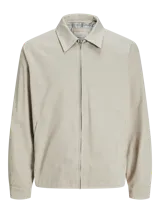 Campera aviadora color beige, de corte clásico, con cuello camisero, cierre frontal con cremallera, bolsillos laterales y puños elastizados.