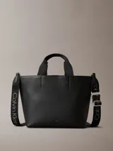 Mini cartera tote Calvin Klein negra de poliuretano con doble asa de mano y correa de hombro ajustable extraíble con el logo de la marca. Cierre con botón a presión y bolsillo interior para tarjeta.