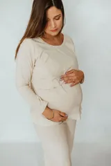 Pijama largo de algodón color beige, apto para embarazo y lactancia. La remera de manga larga cuenta con apertura para amamantar y detalles de puntilla elastizada. El pantalón cuenta con elástico ajustable y detalles de puntilla elastizada.