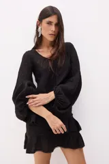 Top blanco de lino italiano con escote en V, mangas largas estilo globo y jareta ajustable en la parte delantera que crea un efecto fruncido y volado en el ruedo.