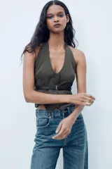 Top de cuello halter color verde oscuro, con escote pico, falso bolsillos de vivo en delantero y cinturón negro con hebilla metálica. Cierre frontal con cremallera oculta.