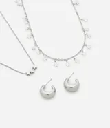 Conjunto de collar de doble cadena plateada con colgantes de estrellas y aros tipo argolla.