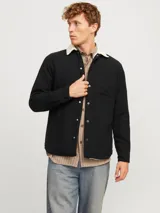 Sobrecamisa negra de manga larga con cuello clásico y fit relajado. Tiene cierre de botones, un bolsillo en el pecho y forro interno de borreguito color crema.