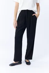 Pantalón de vestir negro, de corte carrot, con pinzas en la cintura y bolsillos laterales.