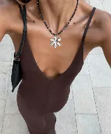 Collar de cuentas negras facetadas con dije de flor plateada.