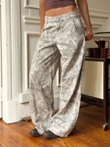Pantalón baggy gris con estampado abstracto en tonos beige y blanco.